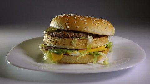 Fried potato chips falling down on hamburger, slow motion, fast food, junk food concept.