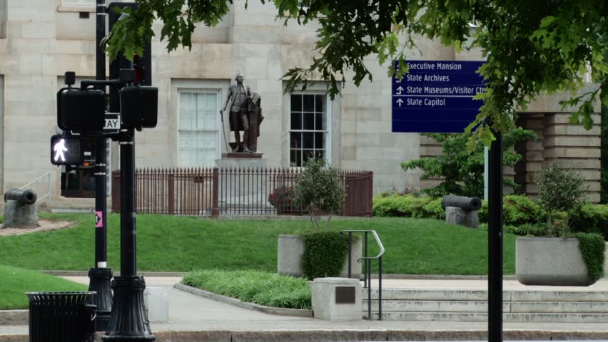 Raleigh, North Carolina State Capital Building with man in suit walking on sidewalk, car traffic, and pedestrian countdown signal