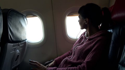 Young woman listen to music on cellphone during plane flight
