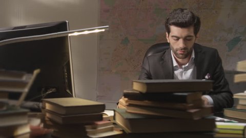 Businessman working and exploring books in the working room. Shot on RED EPIC Cinema Camera.