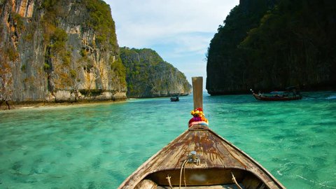 FullHD video - Crystal clear waters under Phi-Phi Island's seacliffs. from across the weathered wooden deck of a handmade longtail boat in Thailand