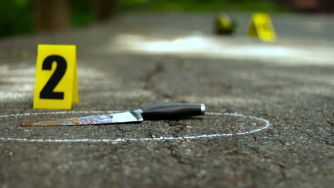 Crime scene with bloody knife and shoe that fell off. Yellow markers placed with the evidence.