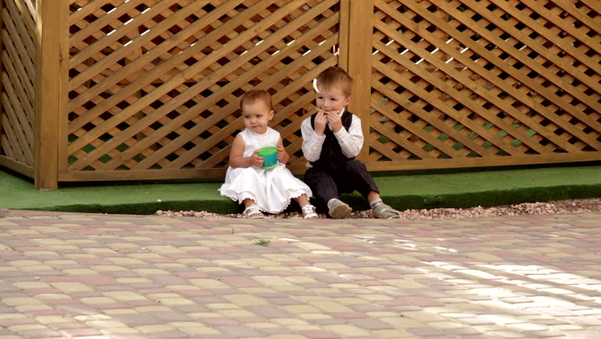 little boy and girl sitting near the gazebo and eat
