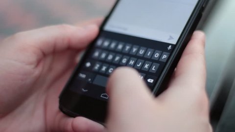 Extreme closeup of person texting on smart phone keyboard.