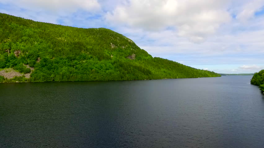 Establishing reveal of a standup paddle boarder immersed in natural sunlight and surrounded by mountains.