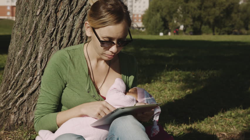 Girl sitting on the grass in the Park and use tablet 