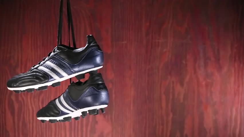 Soccer shoes and ball rotating on reflective surface.