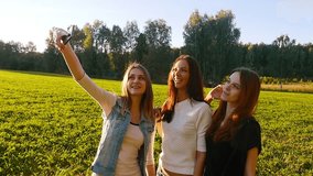 Three friends, young pretty girls, caucasians, having fun outdoors in nature, slow motion.