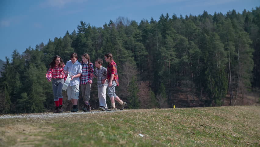 Kids are standing in the middle of the path and looking on the map and finding where they are, footage in slow motion.