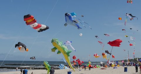 LEBA/POLAND - AUG 29 2015: Dozens of kites are soaring in the sky during the International kite festival in Leba, Poland. People are flying the kites in the sand of the beach on the Baltic sea shore.