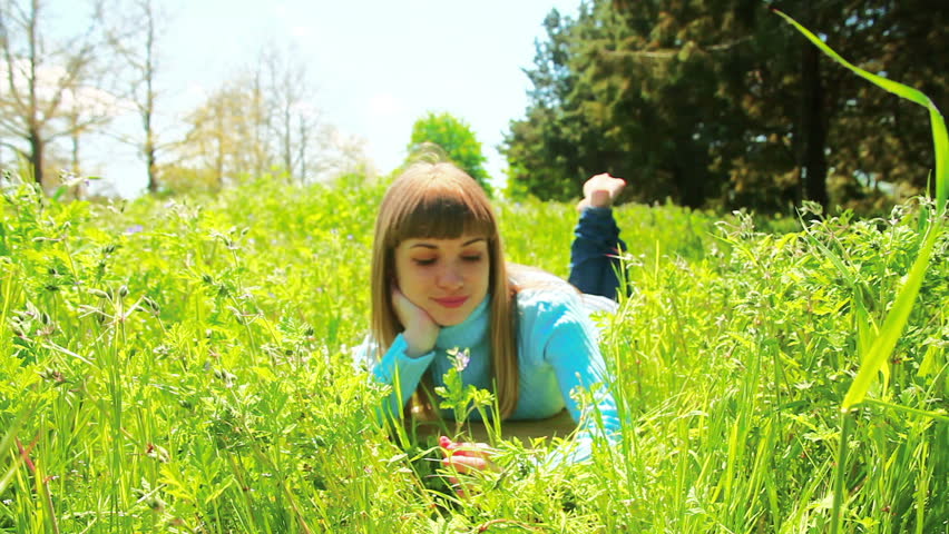 Beautiful woman lying in the grass. Look at camera. Dolly zoom in.