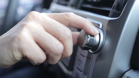 Tuning Radio Volume. Close up of hand adjusting car radio volume