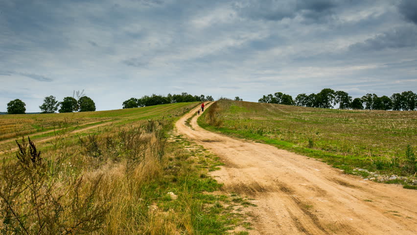 4k timelapse with people walking by rural road under sky with clouds.