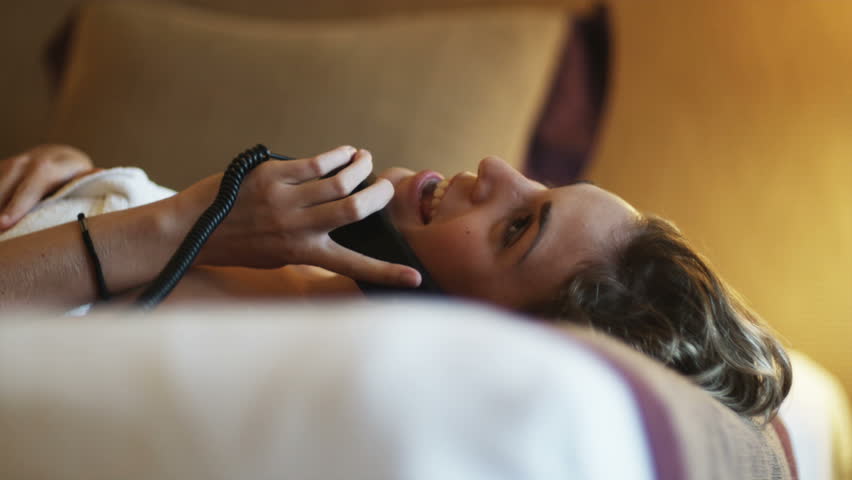 woman lying on a bed talking on the phone