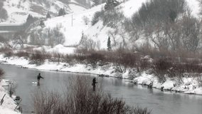 Video of two fishermen fly fishing in Provo River, central Utah. Winter during a snow storm. Cold weather. 