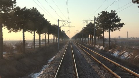 4K POV Point of view of train pass near green tree at sunset or sunrise in winter, snow by day