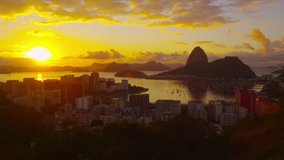 RIO DE JANEIRO - CIRCA JUNE 2013: Lens flare and large setting sun tracking shot over Botafogo Bay. Video captures the marina, Twin Brothers Mountain, and the high-rises of Rio.
