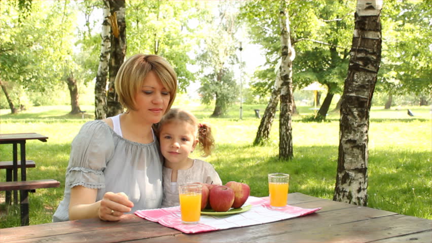 mother and daughter eat and drink in park
