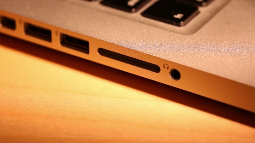 Extreme close up of someone inserting and removing an SD card into a laptop