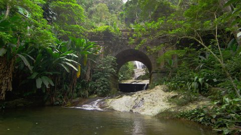 RIO DE JANEIRO - CIRCA JUNE 2013: Tracking shot of a lush jungle waterfall seen through a masonry arch in Tijuca National Park, Rio de Janeiro, Brazil. Filmed June 24, 2013.