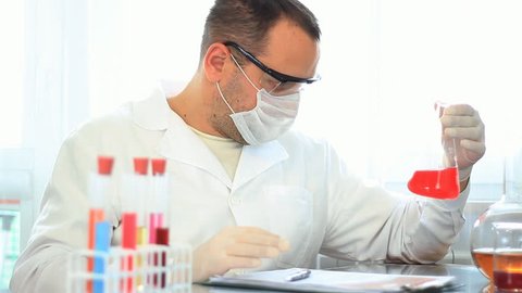 Male scientist working in lab, takes off protective mask and smile to camera