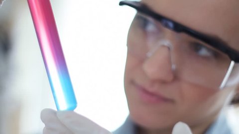 Female scientist looking at test tube with colorful liquid
