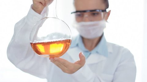 Female scientist mixing chemicals in volumetric flask 