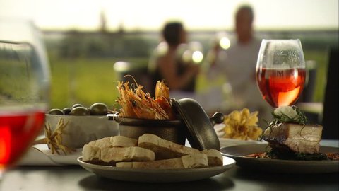 Footage of romantic couple alfresco fine dining meal outdoors amongst vineyards in winery with wine on table, seafood menu with vine views. Australian tourism in Barossa, Clare, Hunter, Yarra, Valley