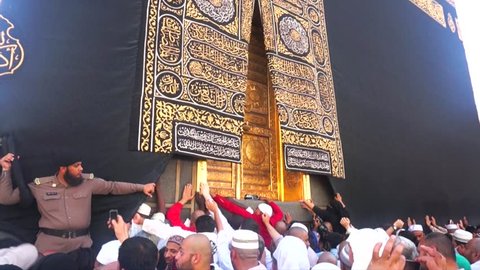 MECCA, SAUDI ARABIA - CIRCA MARCH 2015: Muslim pilgrims pray and touch the Multazam door at Kaaba in Masjidil Haram. Muslims all around the world face the Kaaba during prayer time.