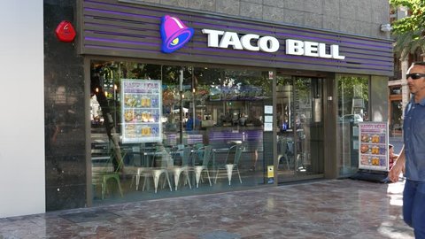 VALENCIA, SPAIN - SEPTEMBER 20, 2015: Tourist walking by a Taco Bell fast-food restaurant. Taco Bell serves more than 2 billion customers each year in more than 5,800 restaurants.