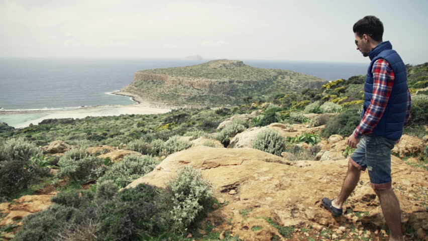 Young man hiking hill and admire view on Balos bay in Crete

