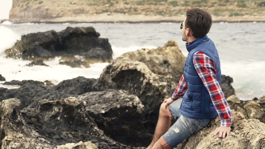 Young man relaxing on rocks and admire view
