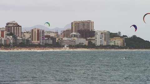 RIO DE JANEIRO - CIRCA JUNE 2013: Panning shot of three visible parasailing surfers. The Copacabana beach and city are in the background. The city is made up of skyscrapers. 