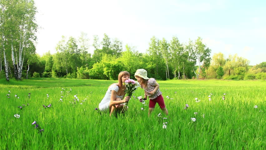 Young mother and child with flowers in the field. Look at Camera. Dolly 