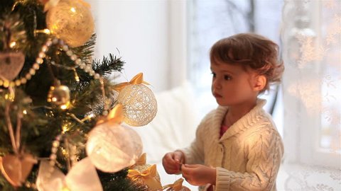 Cute little girl decorates the Christmas tree.