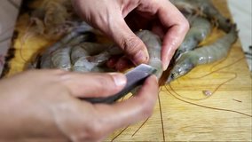 chef peeling shrimp removing the head with the knife preparation to cooking 