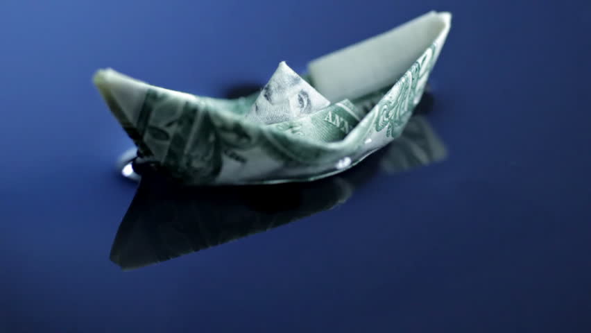 Origami boat made of dollar bill floating