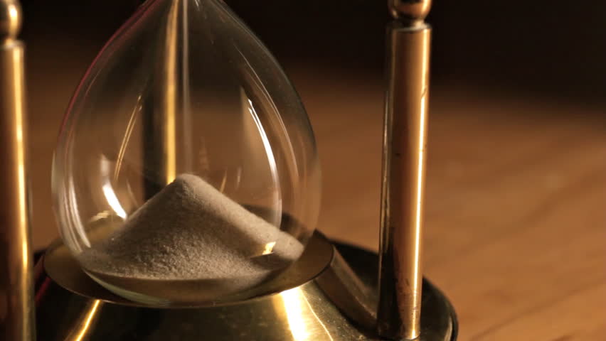 Sand running through old fashioned hourglass