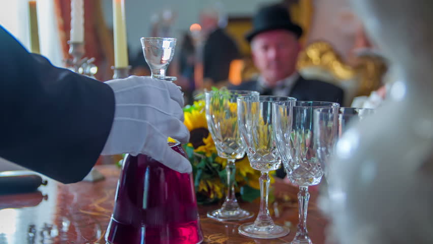 The registrar is taking the red wine and pouring it into glasses at the end of the wedding reception. We can see the best-man in the background | Shutterstock HD Video #11846873