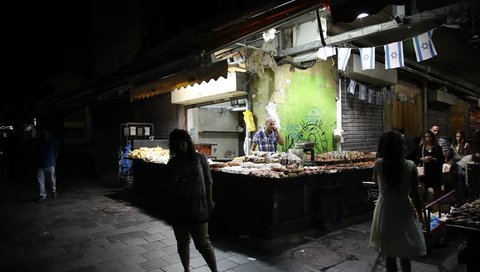 JERUSALEM, ISRAEL - SEPTEMBER 18, 2015: A man sells breads, hala bread and pita bread, cakes, cookies, in Mahane Yehuda Market at night
