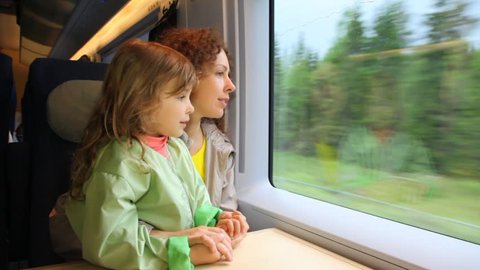 mother with daughter ride in speeding train and look at window