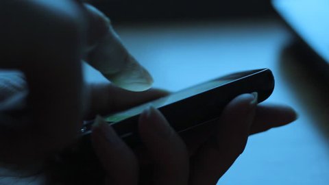Close up of woman using smartphone in dark environment, her hand dimly lit by phone screen - Βίντεο στοκ