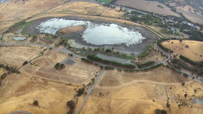 Slowly flying forward over shallow lake with highway in the background