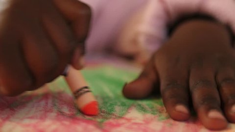 A child's hands use crayons to color at a school in Kenya.