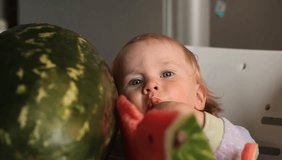 Video baby eats watermelon sitting at the children's table