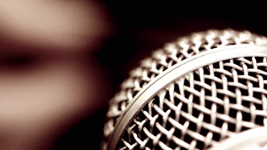 Macro of microphone and finger picking the guitar