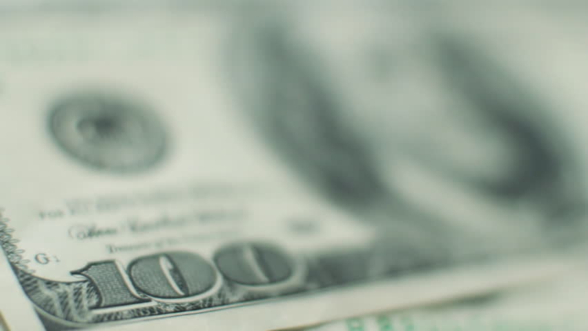 Rack focus across 100 dollar bill settling on Benjamin Franklin's eyes