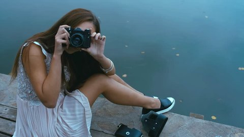 Young attractive Caucasian woman taking pictures with vintage camera on an old pier. HD cinemagraph - motion photo seamless loop : vidéo de stock