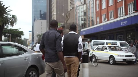 KENYA - CIRCA JULY 2013 - Business men walk in Nairobi city center, tilt to towers, Kenya, Africa
