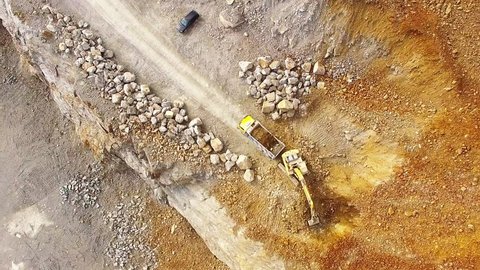 Aerial view of working excavator in the opencast mine. Camera flight over industrial landscape.